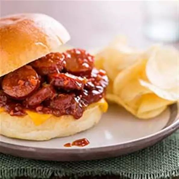 a sandwich with meat and cheese on a plate next to some potato chips in a bowl