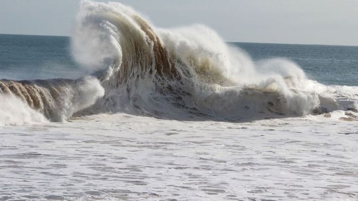 a large wave crashes into the beach as it breaks