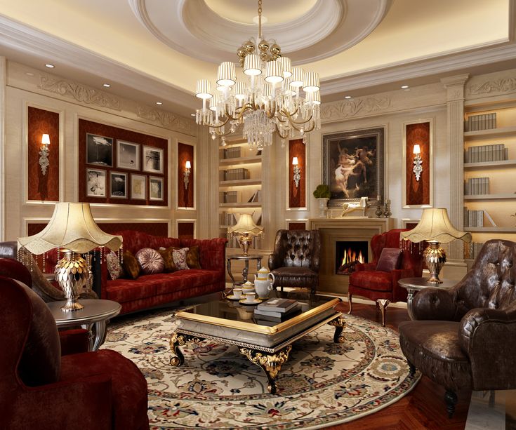 a living room filled with red couches and chairs next to a fire place under a chandelier