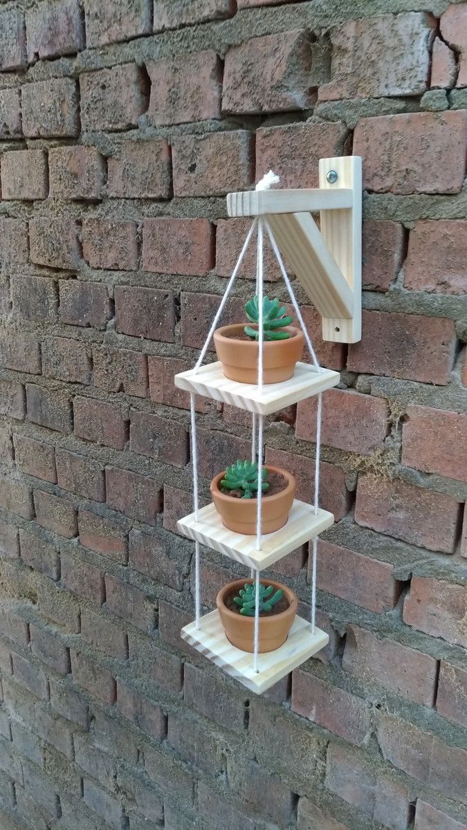 three potted succulents are hanging on a brick wall with a shelf attached to it