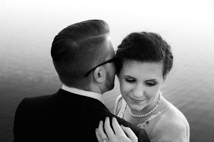 black and white photograph of a bride and groom embracing each other by the water's edge