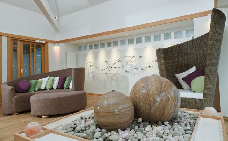 a living room filled with lots of furniture next to a fire place covered in rocks