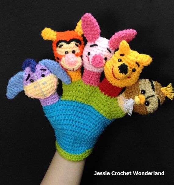 crocheted winnie the pooh and friends finger puppet set on someone's hand