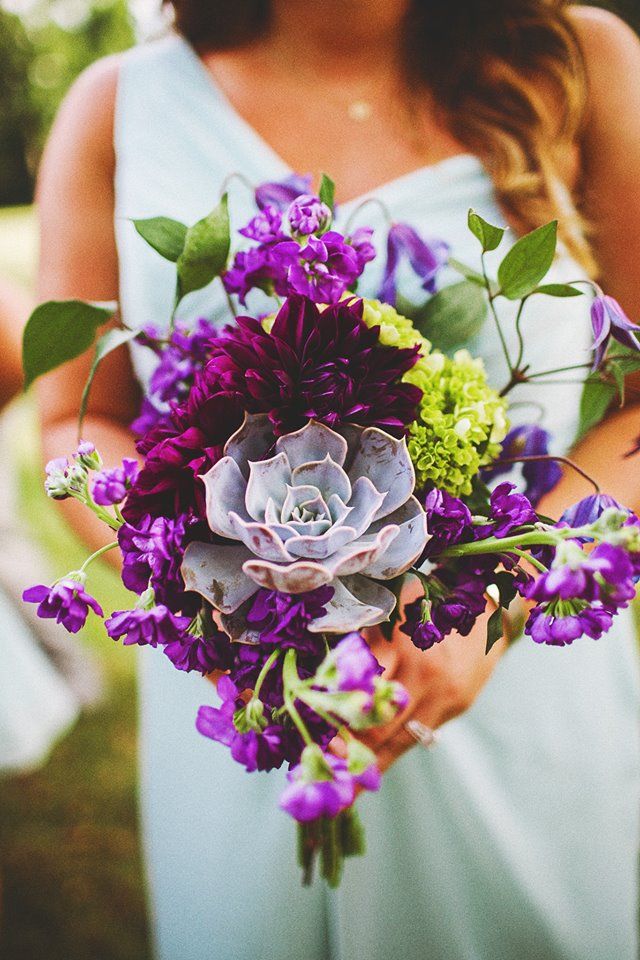 a woman in a blue dress holding a purple and green bouquet