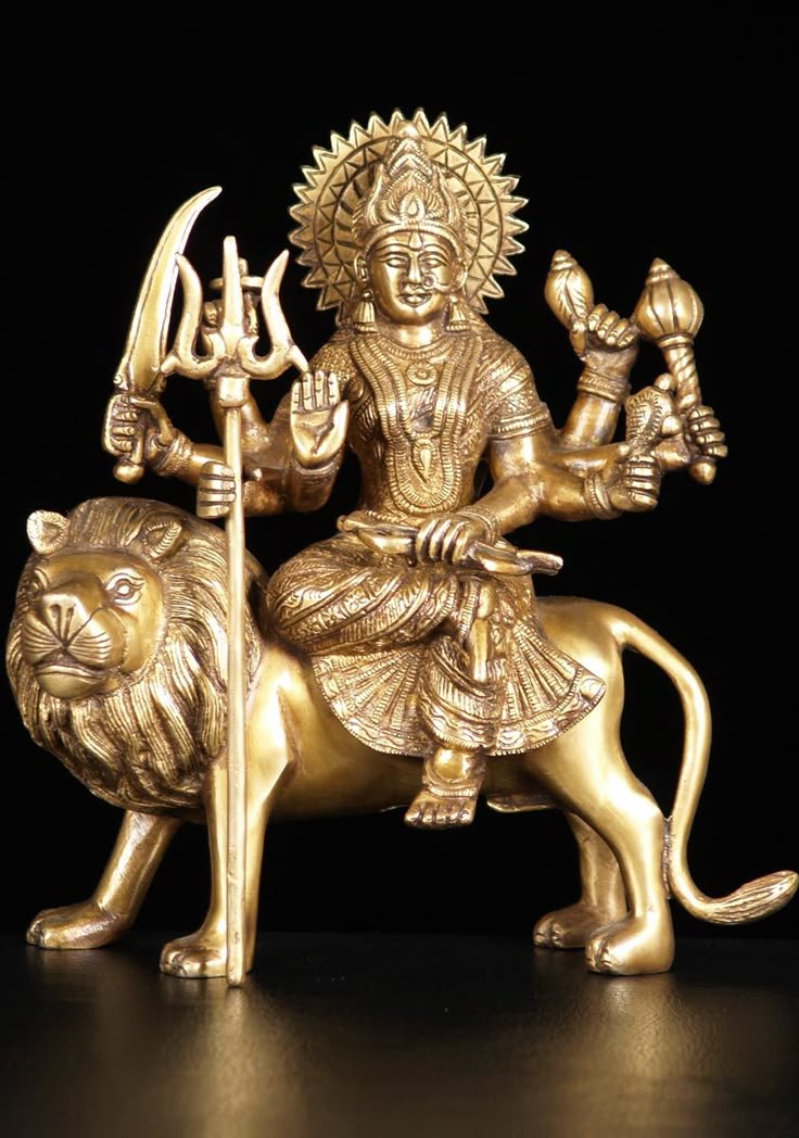 a golden statue of a person on a lion holding a staff and two other animals