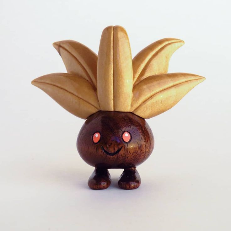 a wooden figurine with large leaves on it's head and two eyes