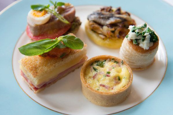 an assortment of pastries on a white and blue plate with green leafy garnishes