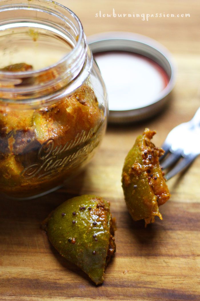 a jar filled with pickles sitting on top of a wooden table next to a fork