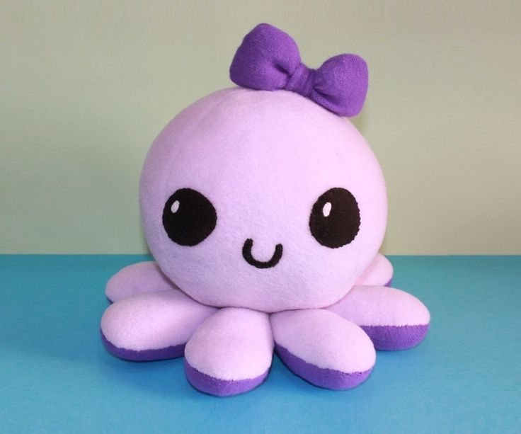 an octopus stuffed animal with a bow on it's head sitting on a blue surface