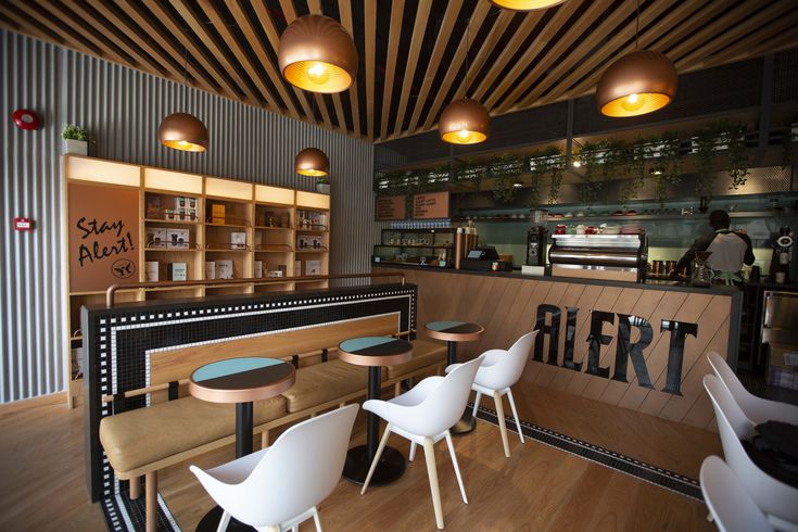 an empty restaurant with wooden tables and white chairs in front of the counter, along with hanging lights