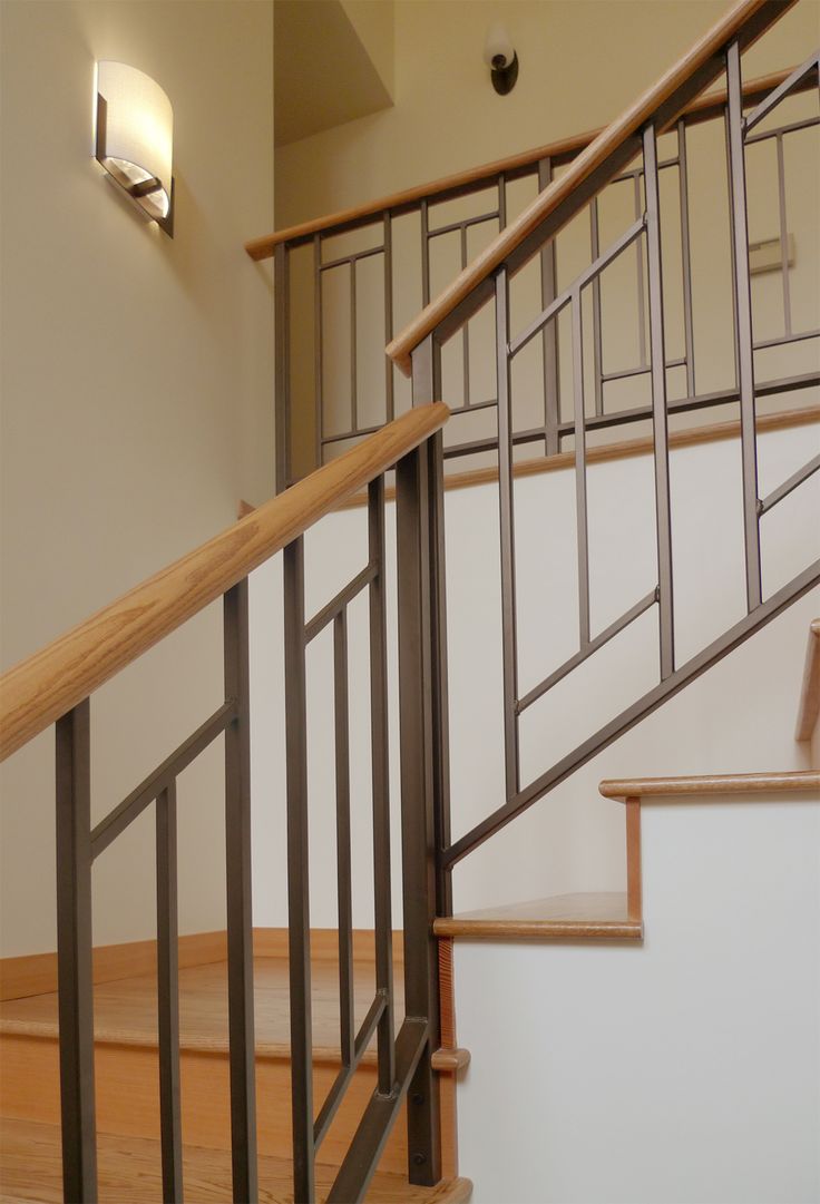 an empty staircase with wooden handrails next to a light on the wall above it