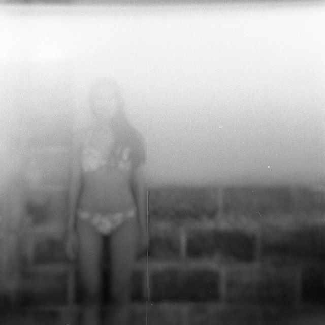 a woman standing in front of a brick wall wearing a bathing suit and holding a frisbee