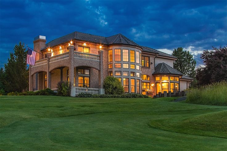 a large house with lots of windows and lights on it's front lawn at night