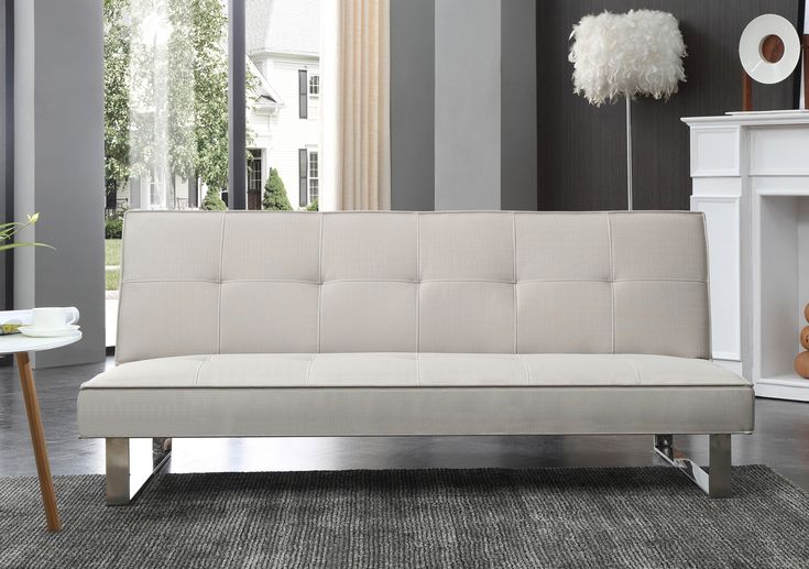 a white futon sofa sitting in a living room next to a fireplace