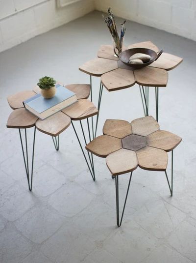 three wooden tables with metal legs and flower designs on each table, one has a potted plant in the middle