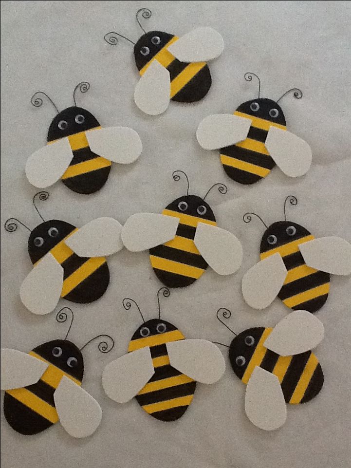 a bunch of paper bees sitting on top of a white table covered in yellow and black stripes