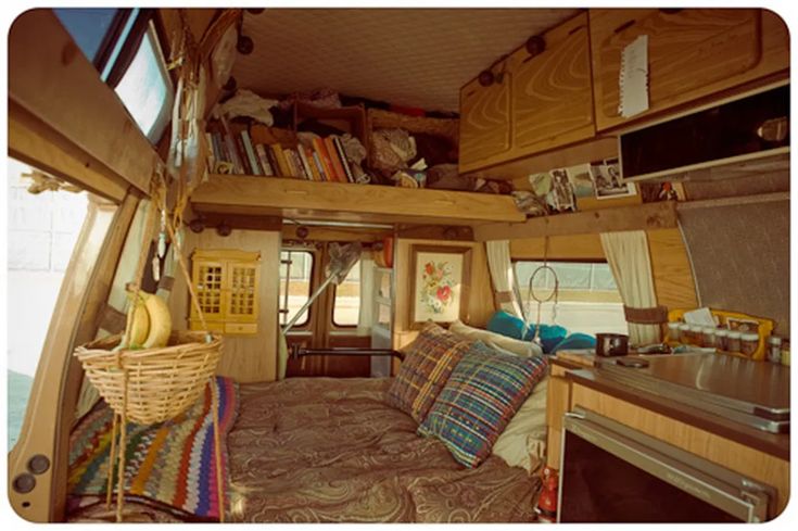 the inside of a camper with a bed, sink and shelves on each side