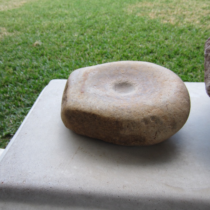 a rock sitting on top of a cement slab in the middle of a field with grass