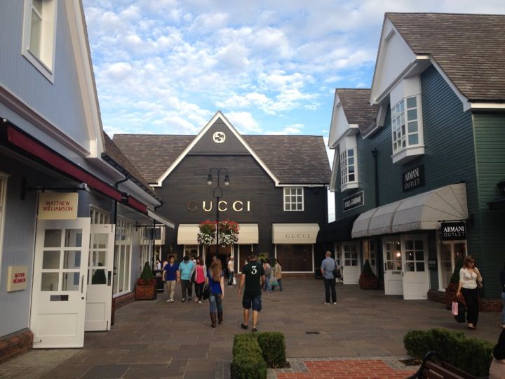 many people are walking down the street in front of shops