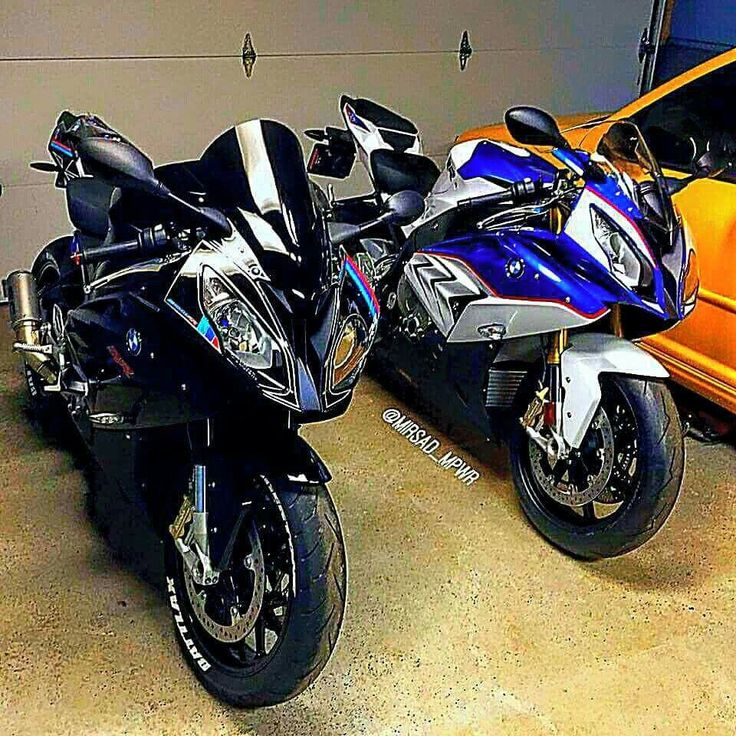 two motorcycles parked next to each other in front of a yellow car and orange truck