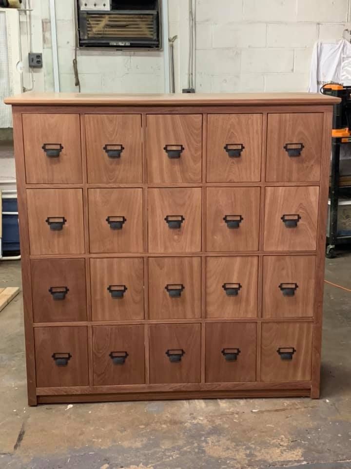 a large wooden cabinet with many drawers in the middle and one drawer on each side