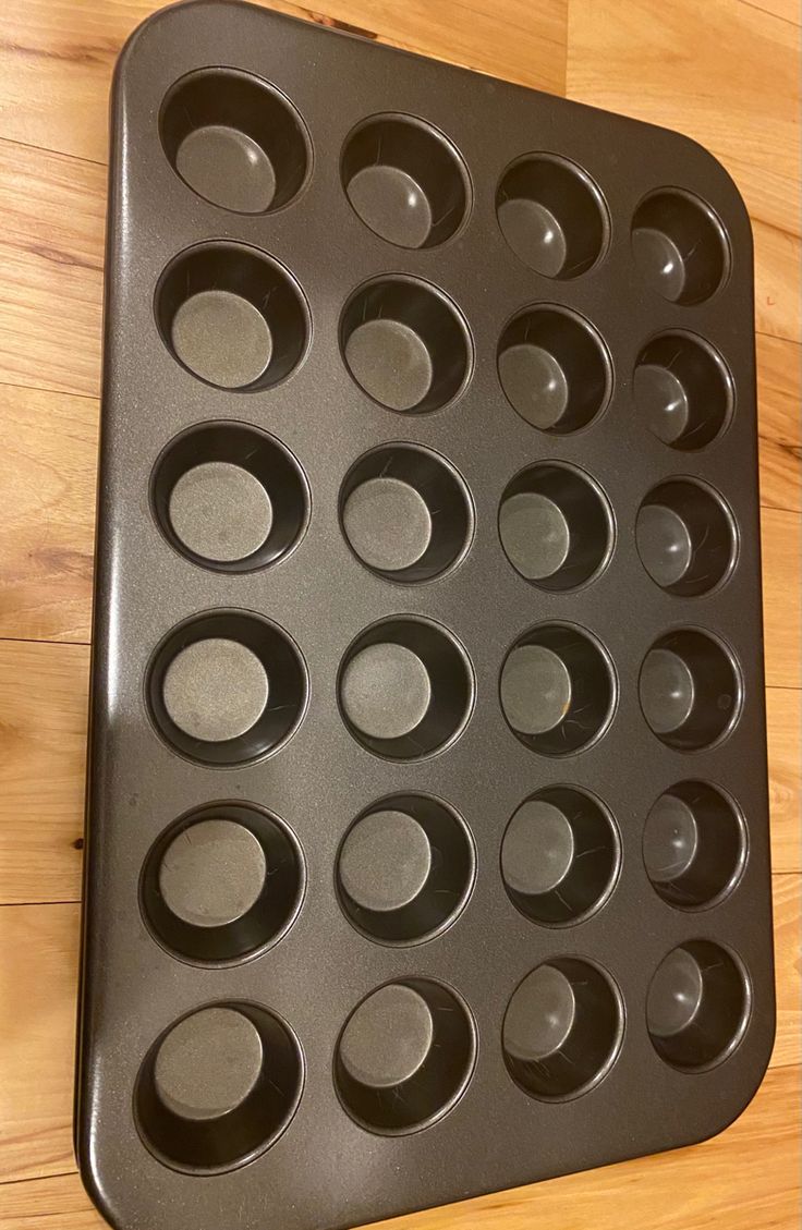 a black muffin pan on a wooden table