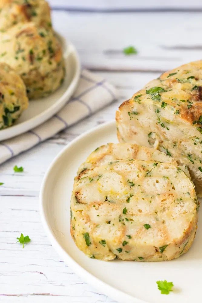 three biscuits on a white plate with parsley sprinkled around the edges, and another biscuit in the background