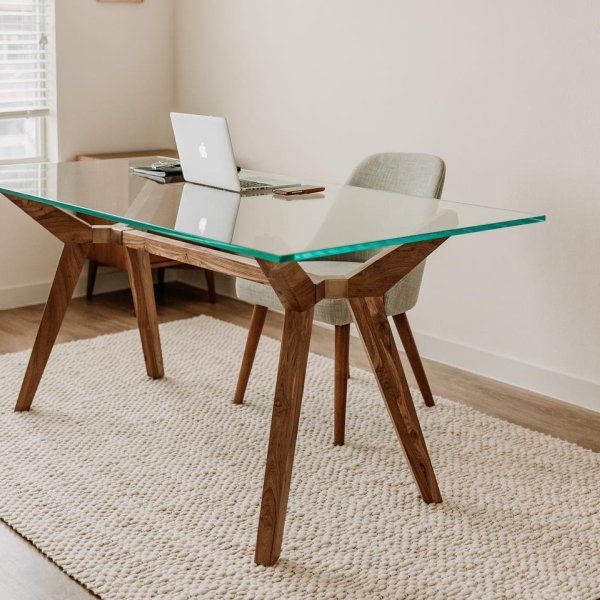 a glass table with wooden legs and a laptop on it