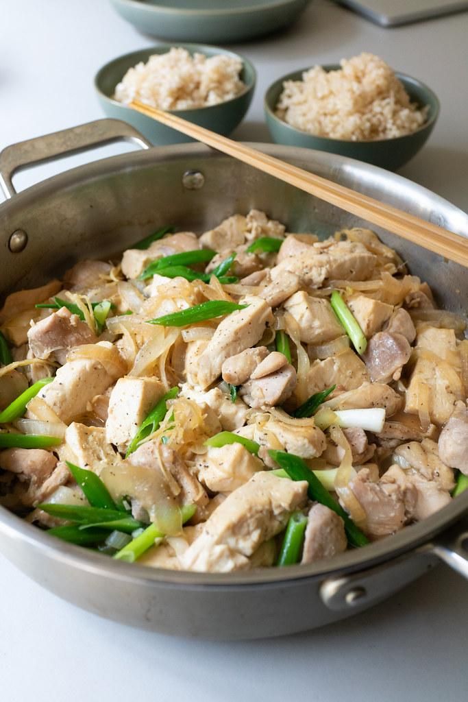 a pan filled with meat and vegetables next to bowls of rice