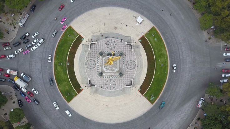 an aerial view of a circular building with a statue in the center surrounded by cars