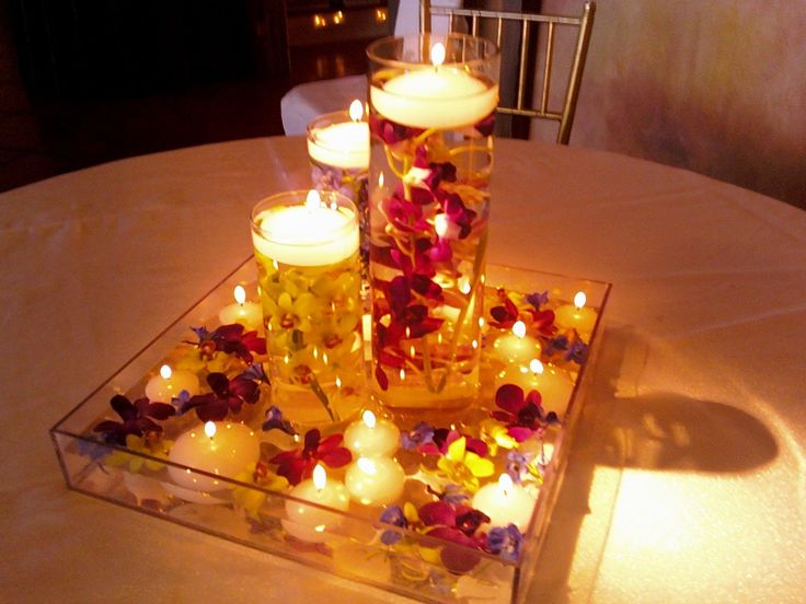 candles are lit on a glass plate with flowers and petals in the shape of a heart