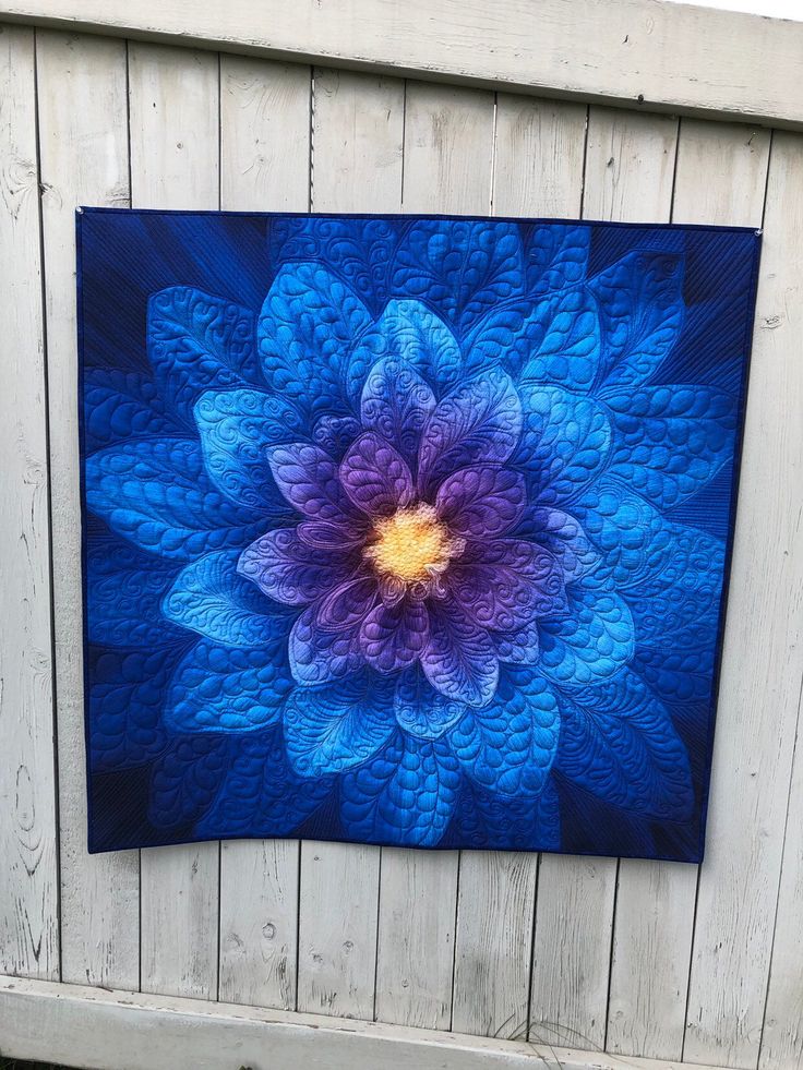 a blue and purple flower is hanging on a wooden paneled wall in front of a white fence