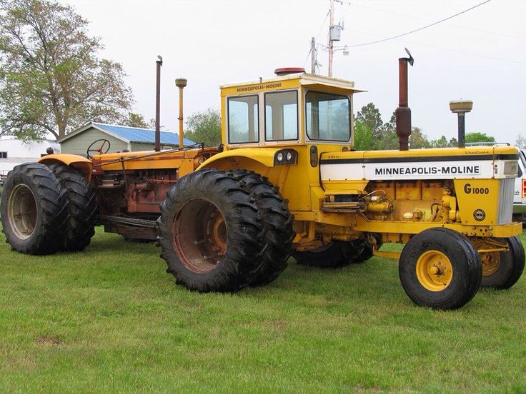 a large yellow tractor parked on top of a lush green field