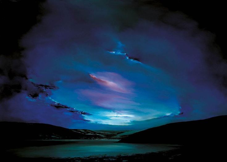 the sky is lit up with blue and purple clouds over water at night, as seen from shore