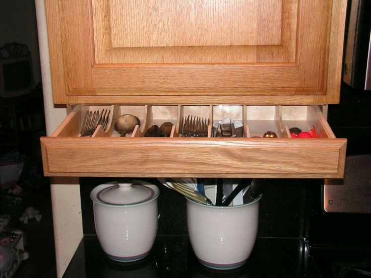 a wooden cabinet filled with utensils and cups