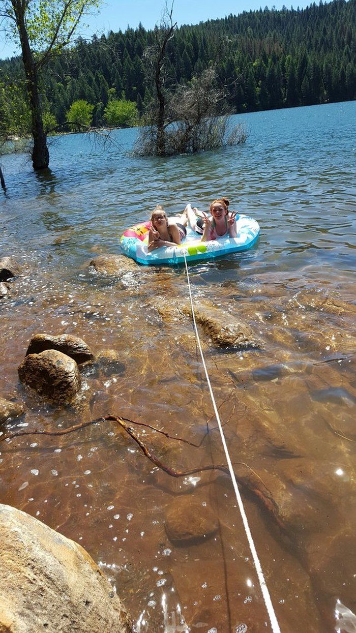 two children are floating on an inflatable raft in the water near some rocks