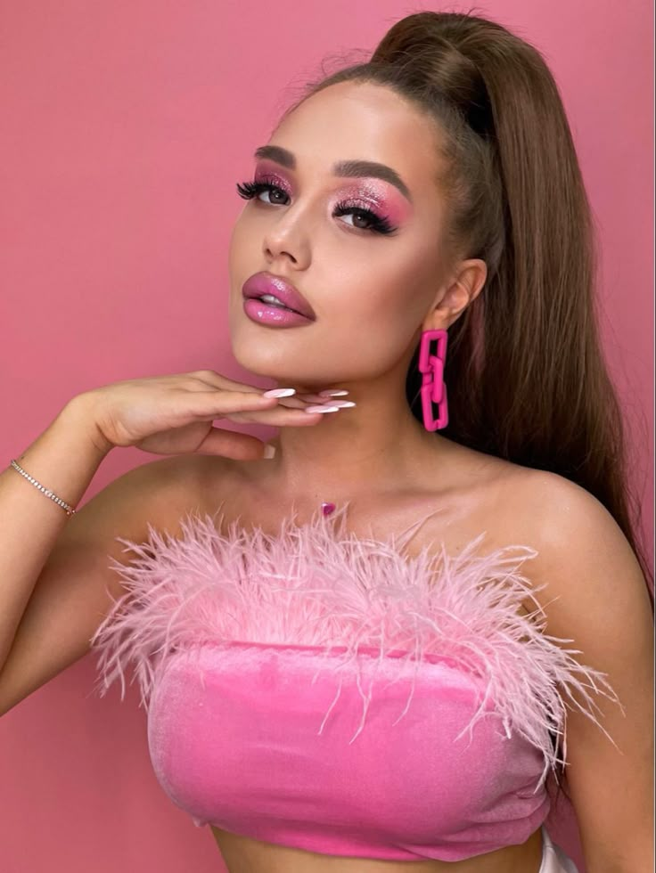 a woman with long hair and pink makeup posing for a photo in front of a pink background