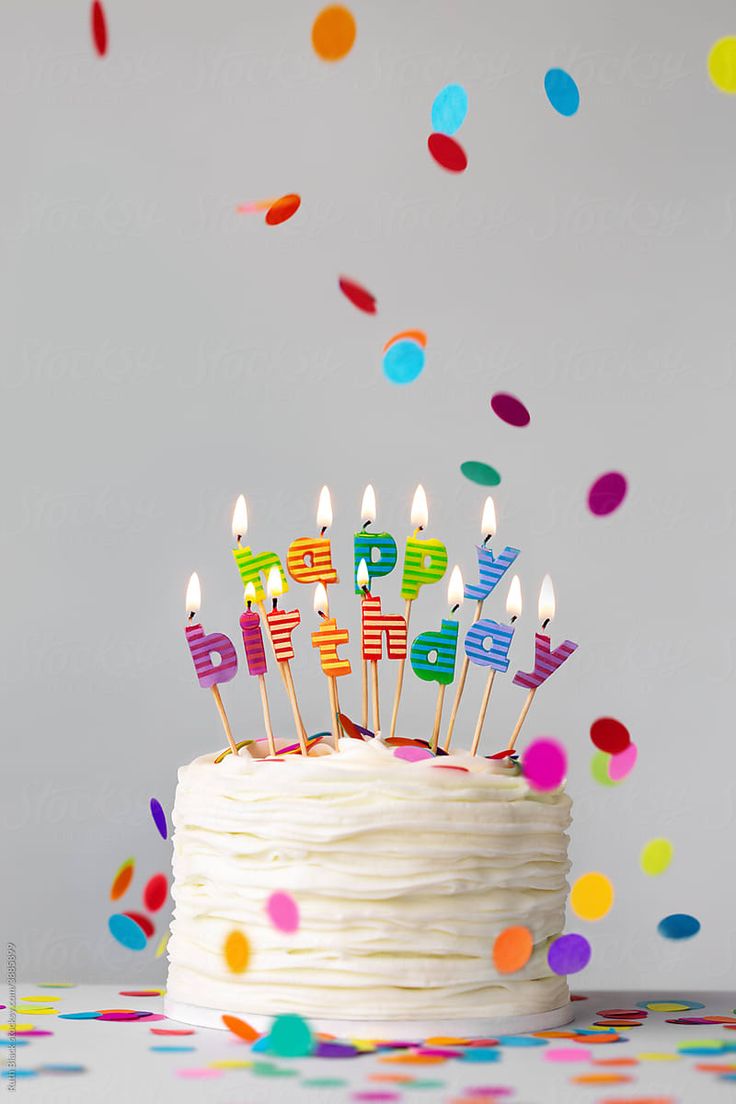 a birthday cake with lit candles and confetti by luma studio for stocksy