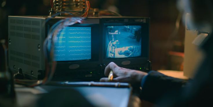 a person sitting at a desk in front of a computer monitor with two monitors on it