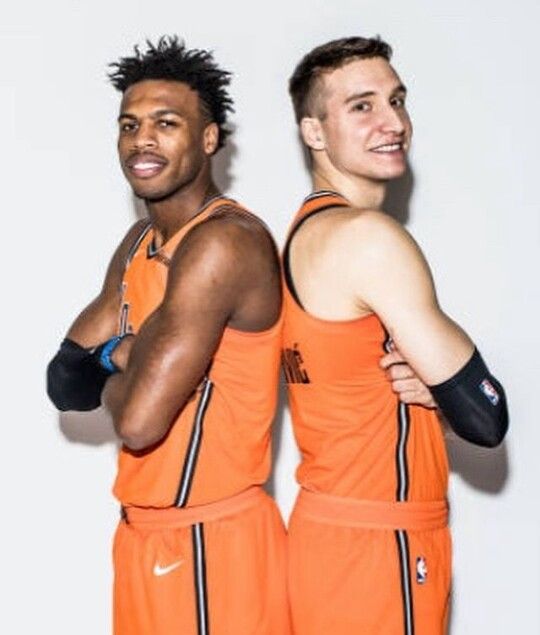 two basketball players in orange uniforms posing for the camera with their arms around each other