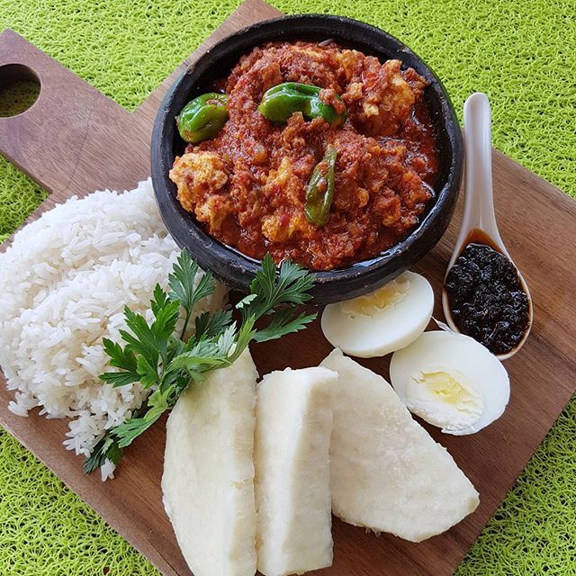 a wooden cutting board topped with rice, eggs and other foods on top of it