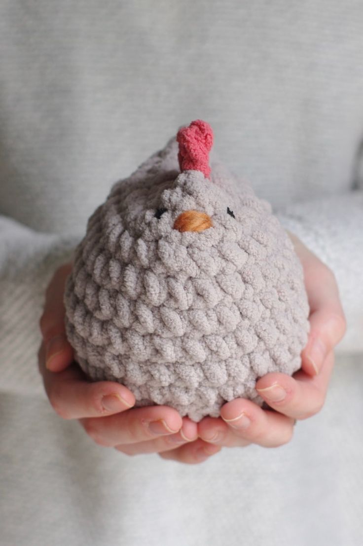 a person holding a crocheted chicken in their hands