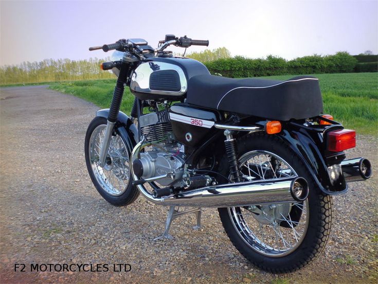 a black motorcycle parked on top of a gravel road