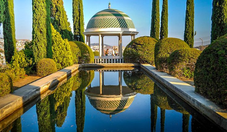 a gazebo surrounded by trees and water in the middle of a park with lots of greenery