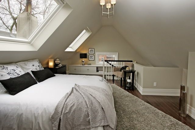 a bed sitting under a window in a bedroom next to a desk and chair on top of a hard wood floor