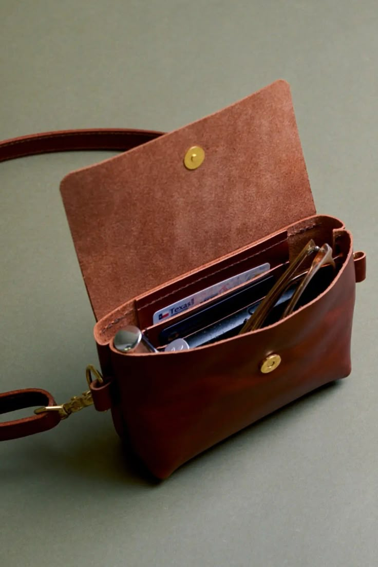 a brown leather purse with cell phone and credit cards in it on a gray surface