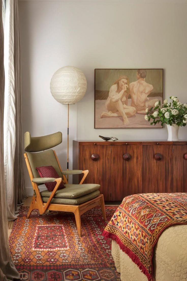 a bed room with a neatly made bed next to a chair and a painting on the wall