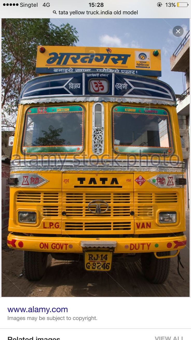 an old yellow truck parked in front of a building with the words tata on it