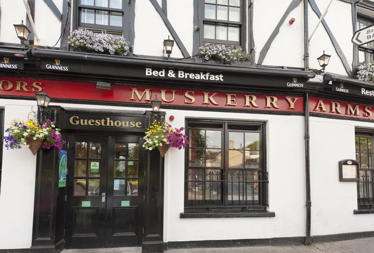 the outside of a pub with flowers hanging from it's windows