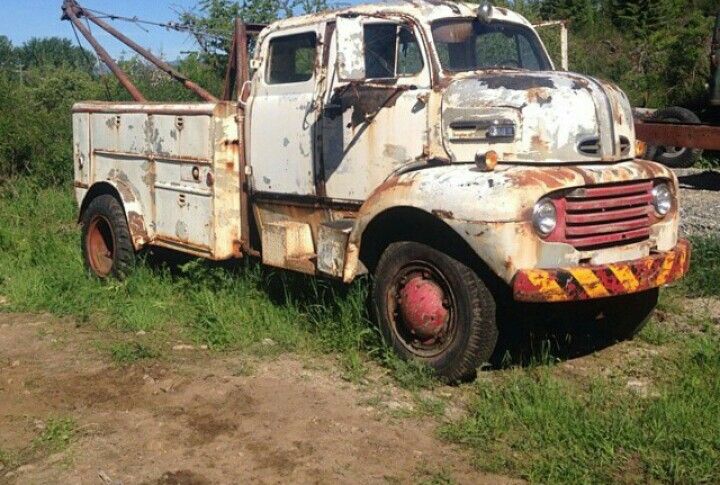 an old rusted out truck sitting in the grass